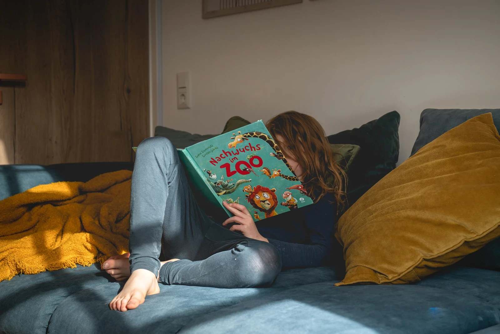 Kind liest auf Sofa