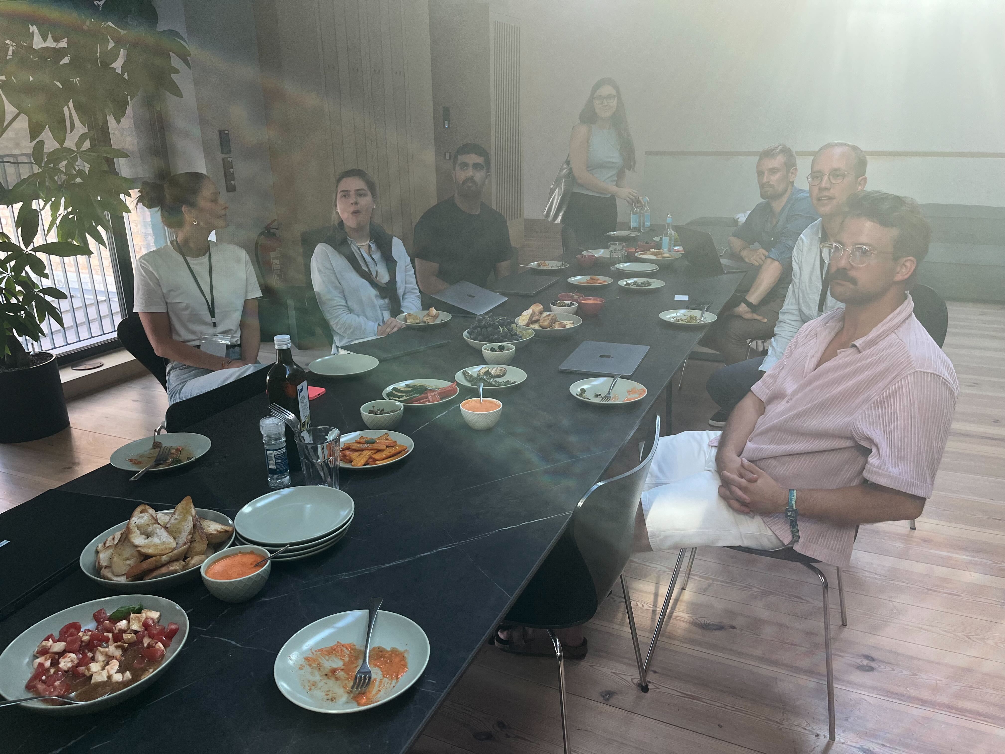 Mitarbeitende von Bridgemaker sitzen bei Tapas gemeinsam am Tisch und brainstormen während des Hackathons