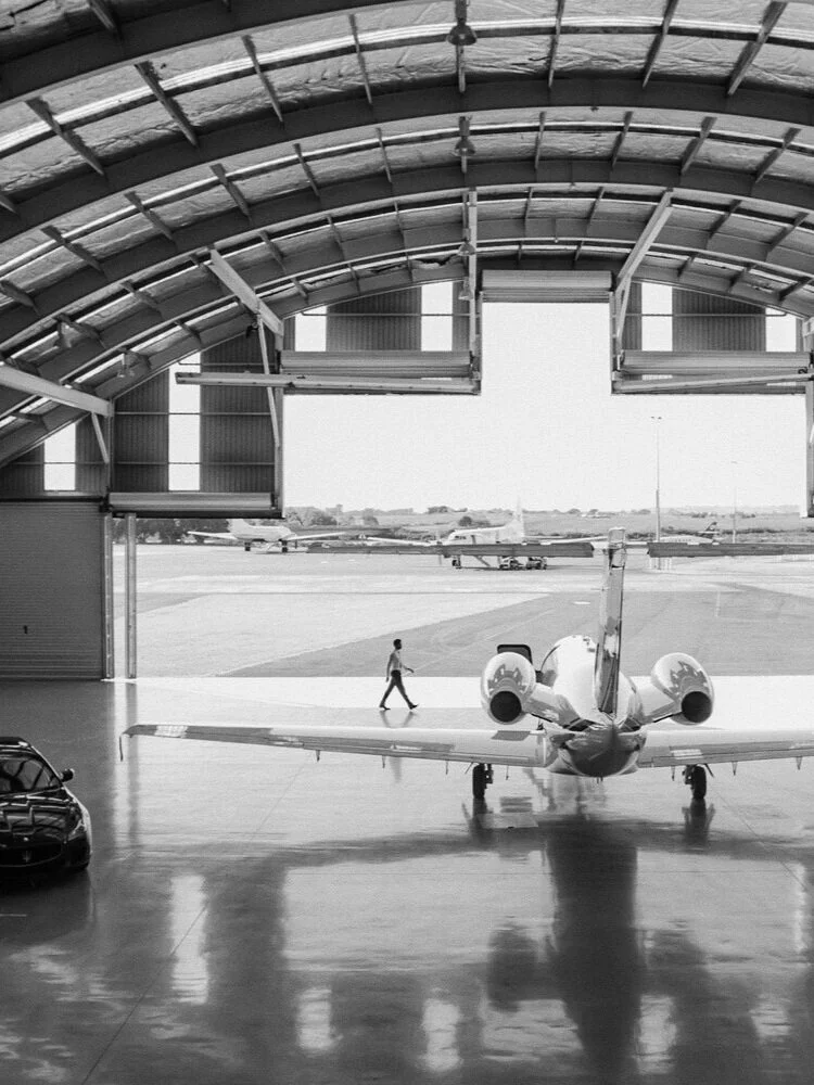 Private jet parked inside a large arched aviation hangar