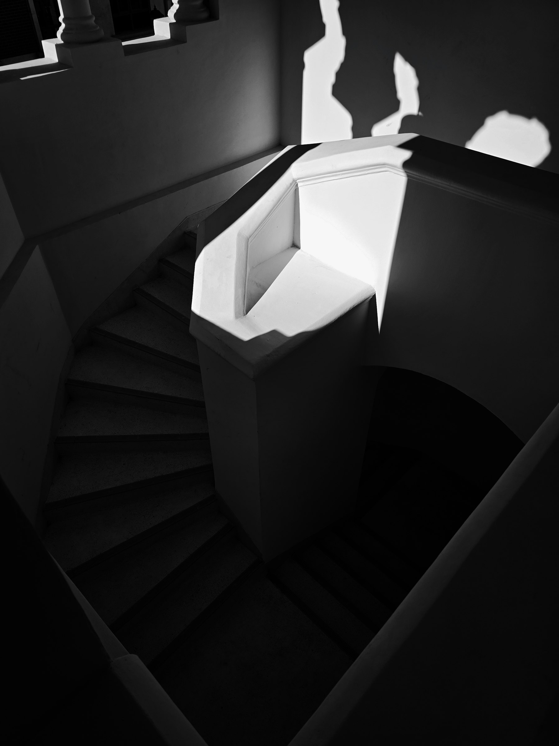Winding white staircase cut by a shaft of sunlight