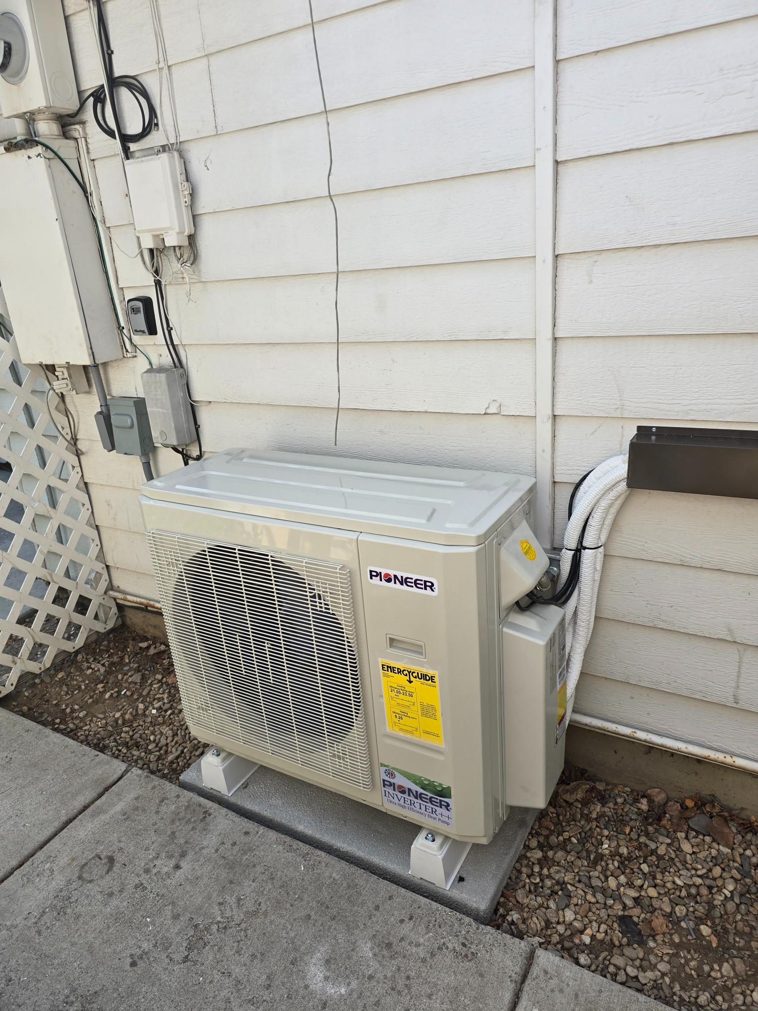 Outdoor Pioneer heat pump system installed against a house exterior.