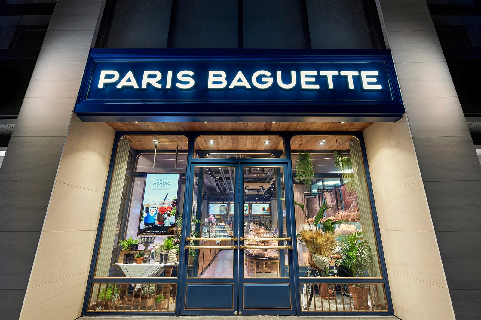 Front view of a Paris Baguette bakery, featuring a blue sign with its name and a glass display of pastries.