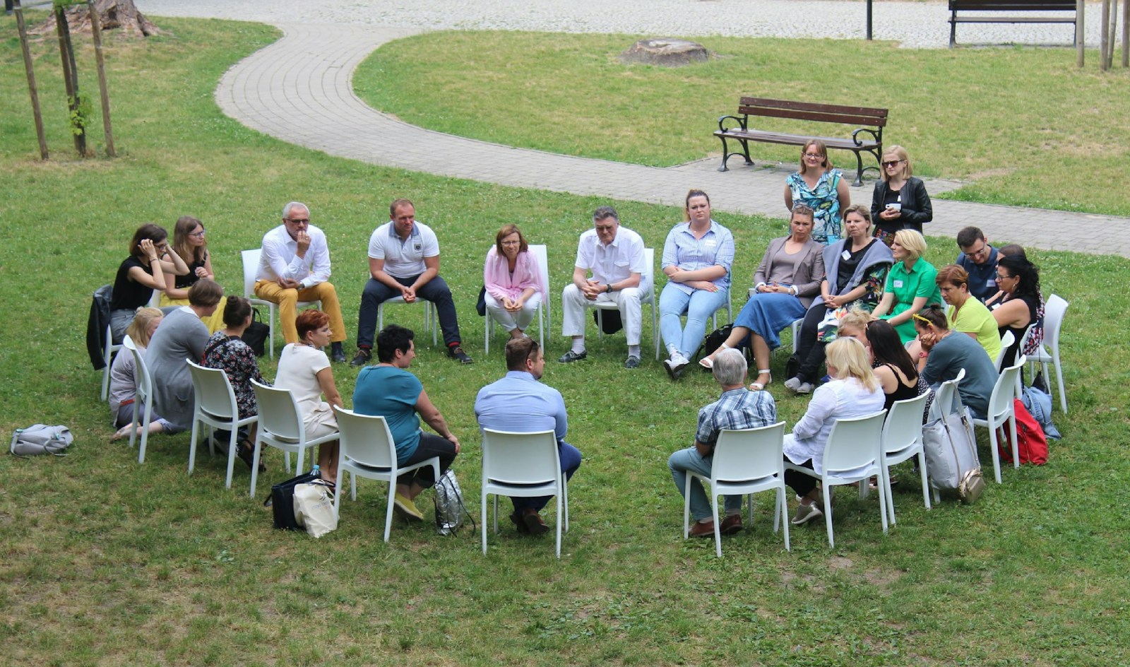 Circle of people sitting on chair on grass fiedl