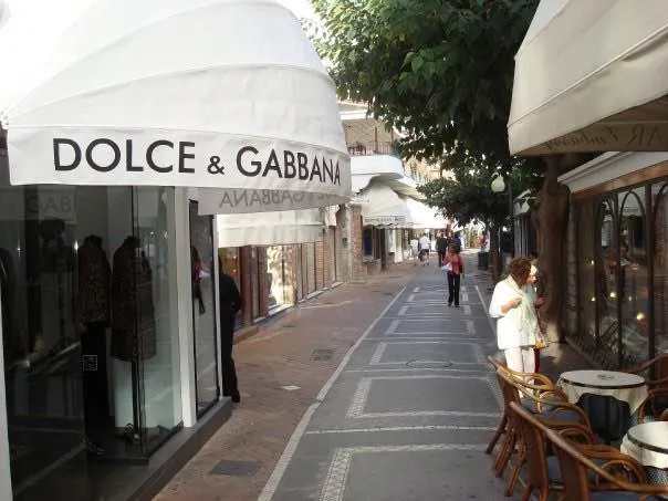 A shopping street on the Amalfi Coast lined with designer storefronts and awnings.
