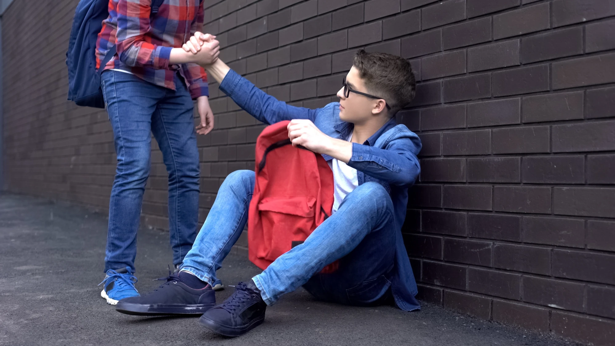 a boy helping his friend stand up