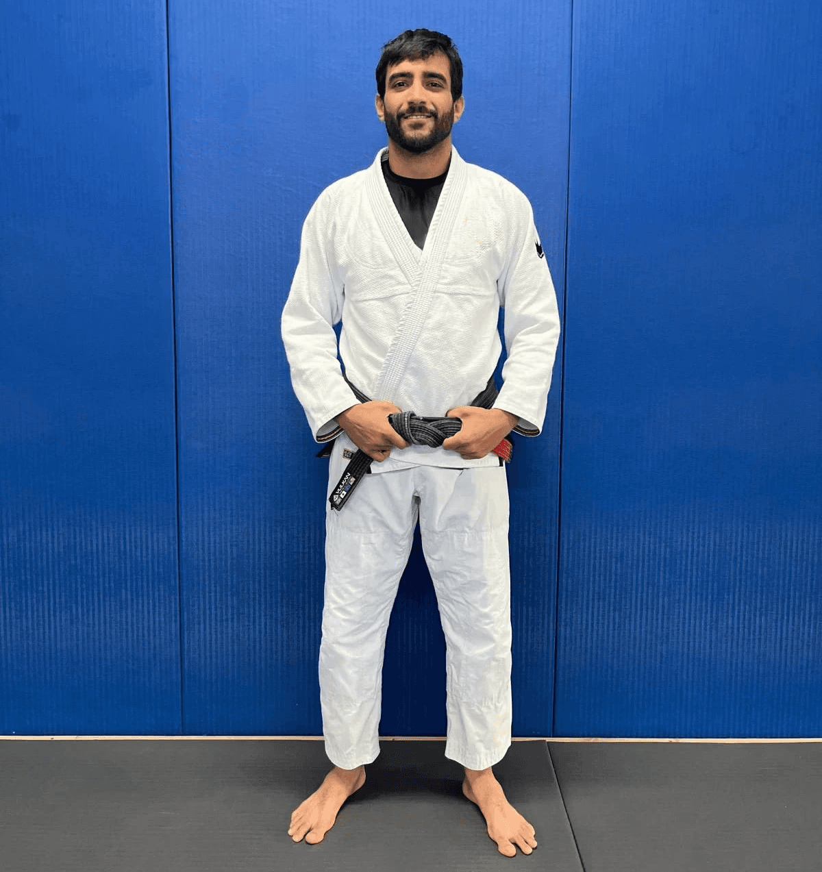 Maria Elisa Thimoteo smiling in her gi, hands folded in front of a gradient backdrop