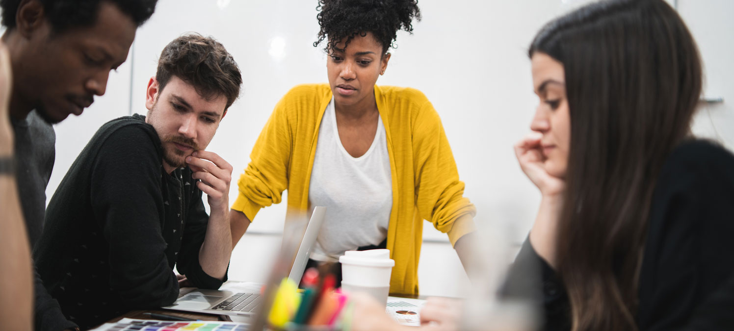 Team reviewing brand strategy materials around a laptop with color swatches and markers on the table