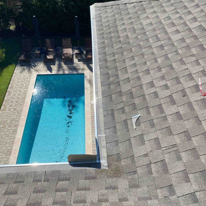 Technician inspecting and flushing gutters to ensure proper water drainage.
