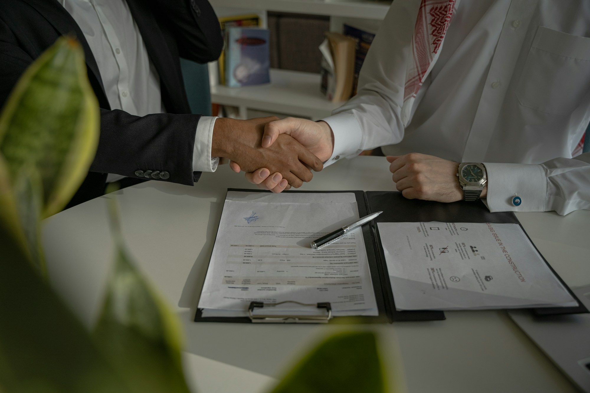 Two people shaking hands over signed documents