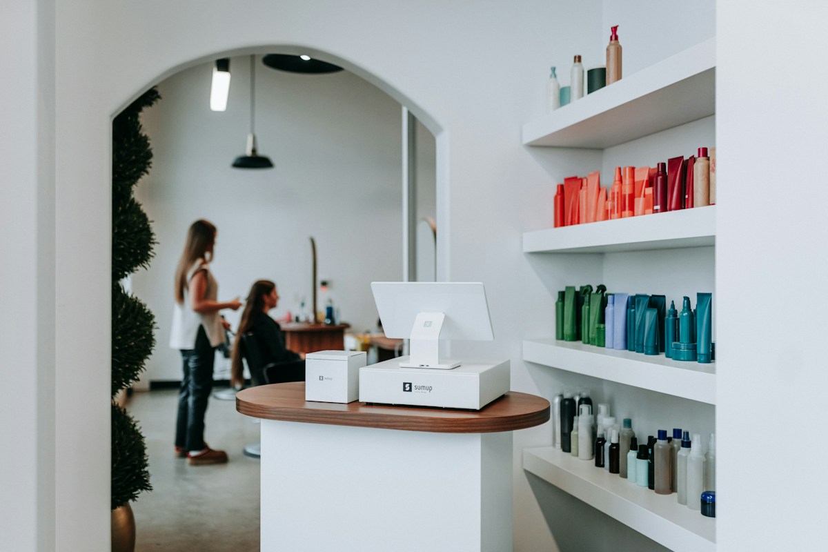 The studio’s bright front desk with an arched doorway and shelves of hair products