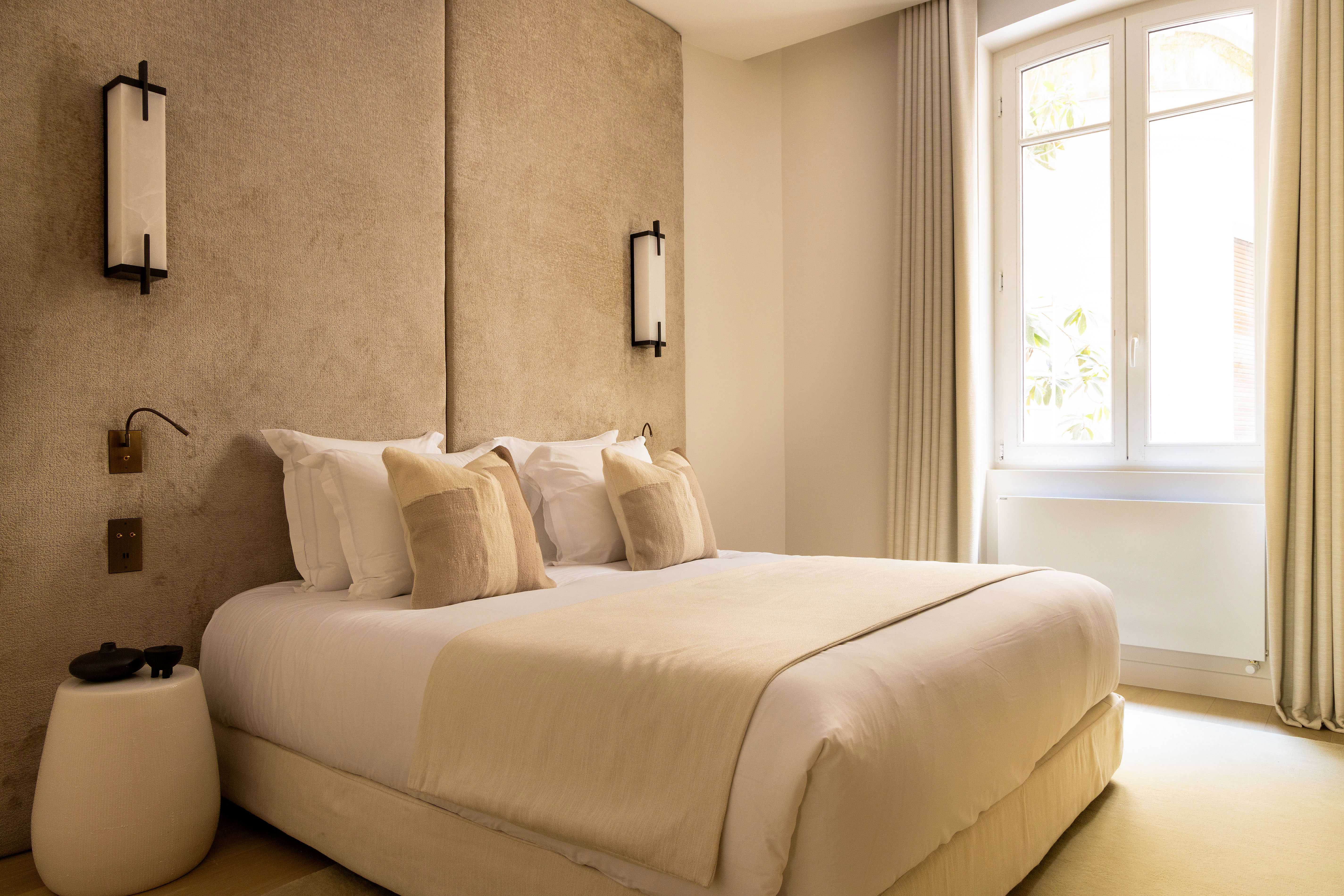 Chambre principale avec lit double, tête de lit velours sable, appliques noires et chevets ronds
