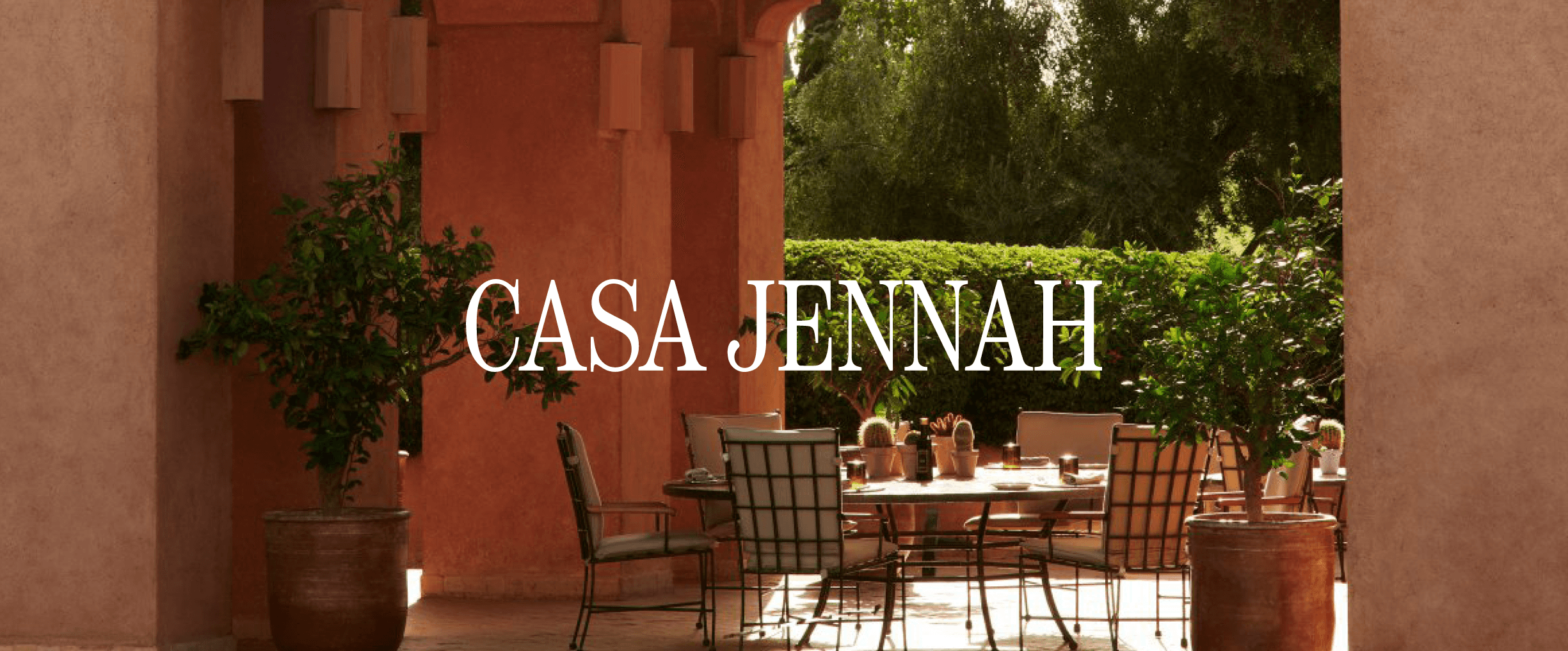 Table à manger en plein air dans une cour verdoyante. Texte "Casa Jennah"