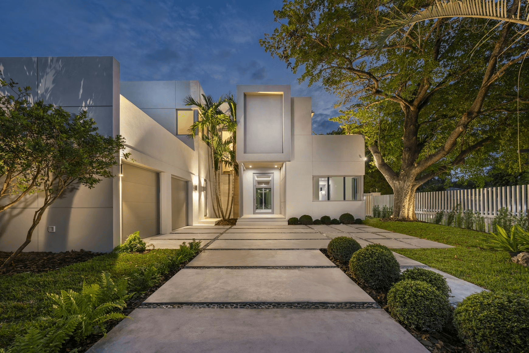 Modern white house at dusk with pathway.