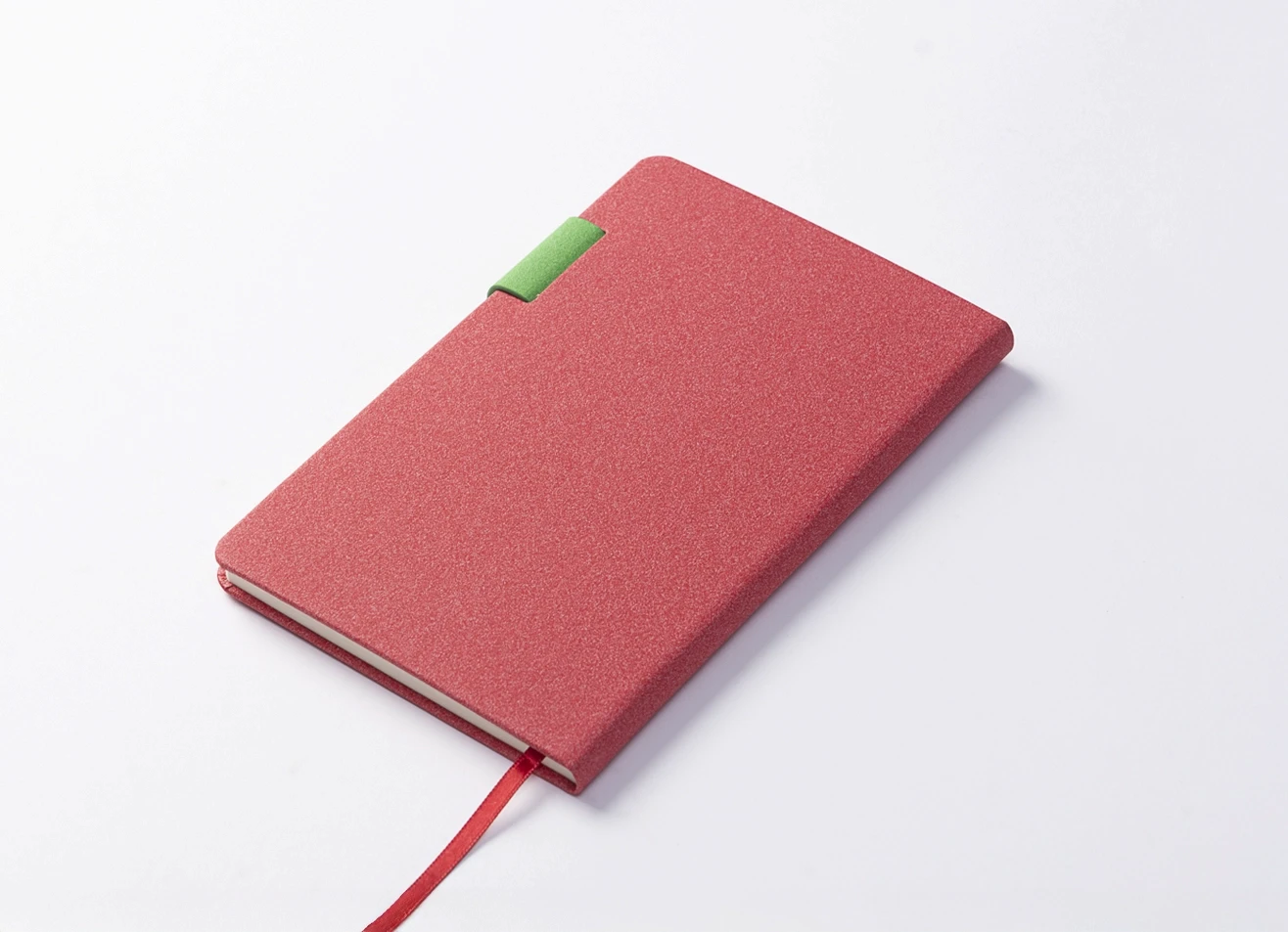 Angled back view of red notebook showing green strap attachment.