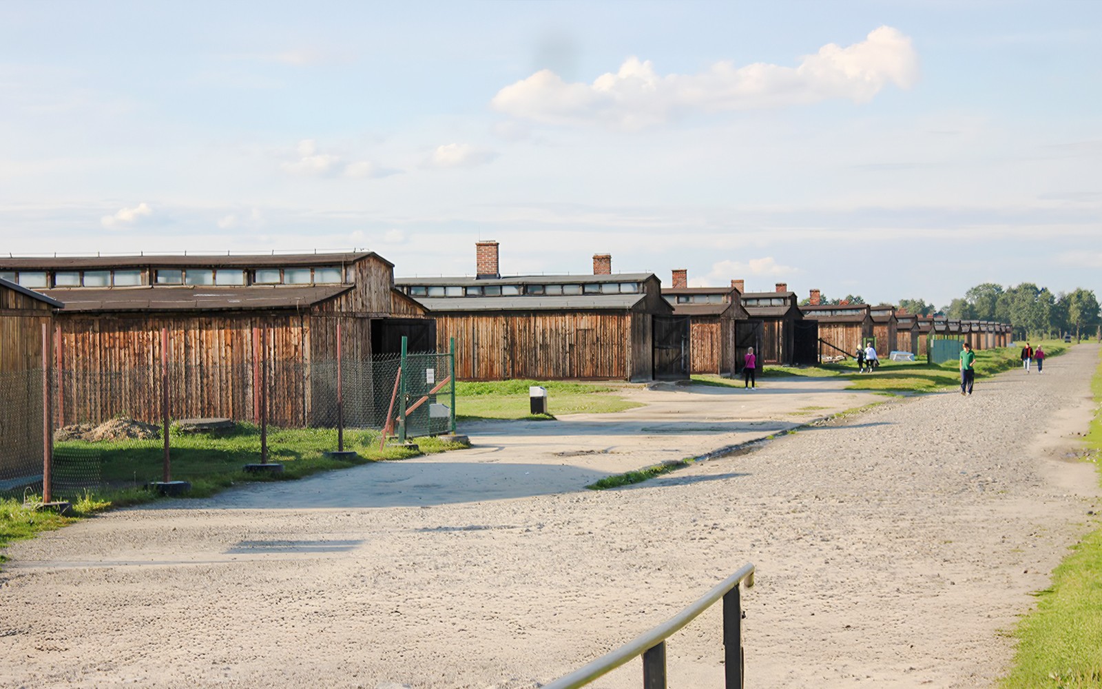 Barakkir Auschwitz-Birkenau með gestum sem ganga eftir möl stígunum.
