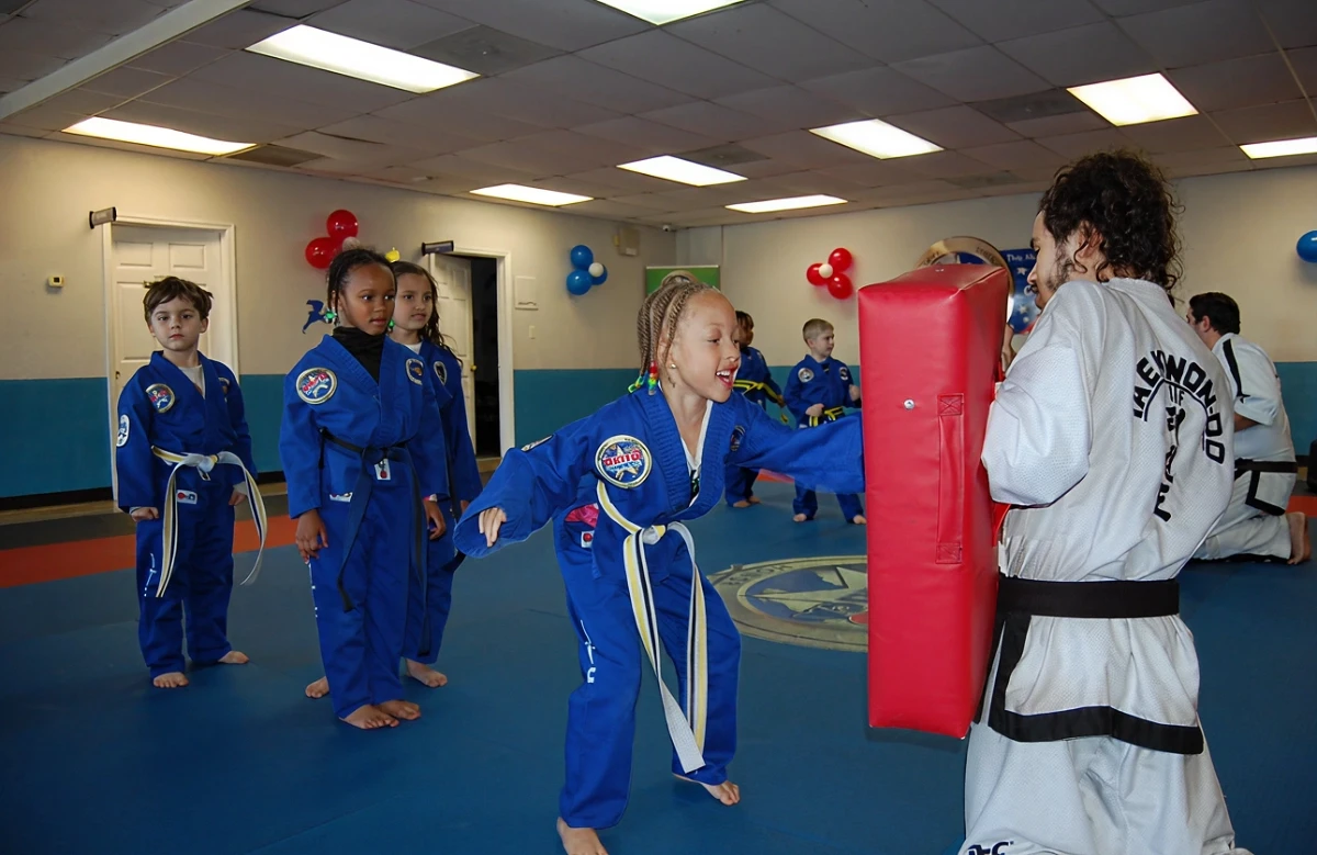 Student punching a board while instructor holds it.