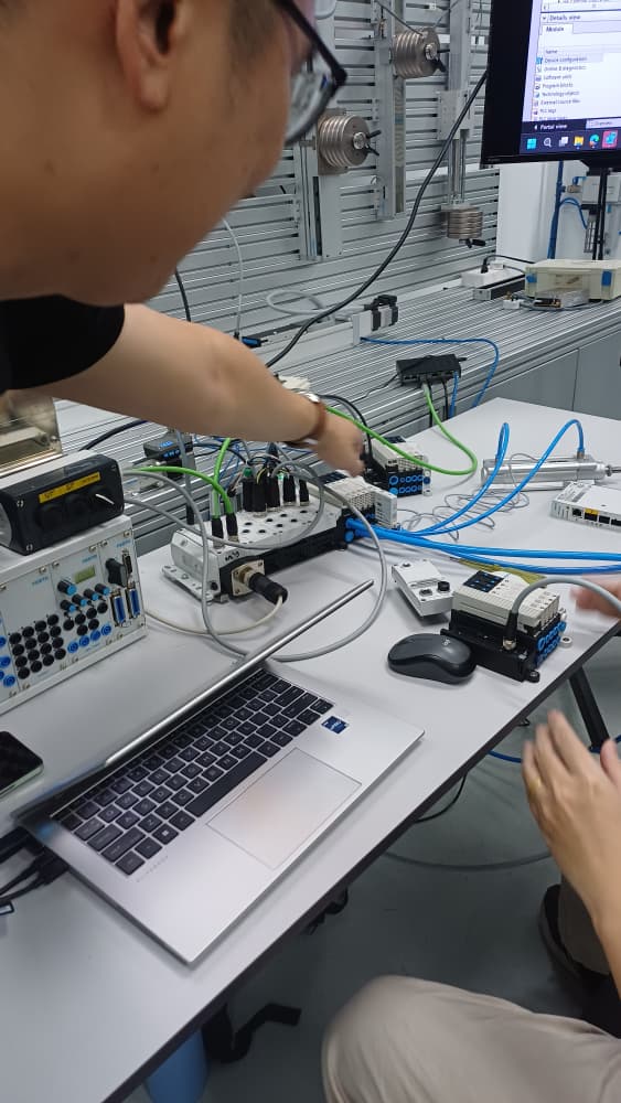 Festo expert guiding Autofill engineers through a practical PLC and pneumatic system setup on the knowledge bench.
