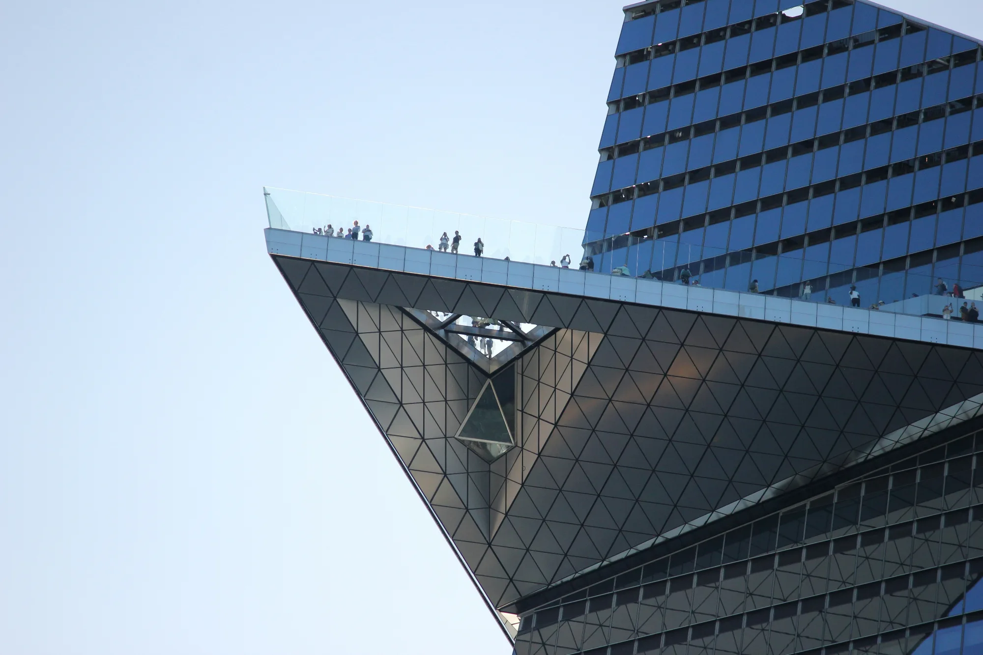 The Edge NYC observation deck, a triangular cantilevered platform on a modern skyscraper with blue glass windows.