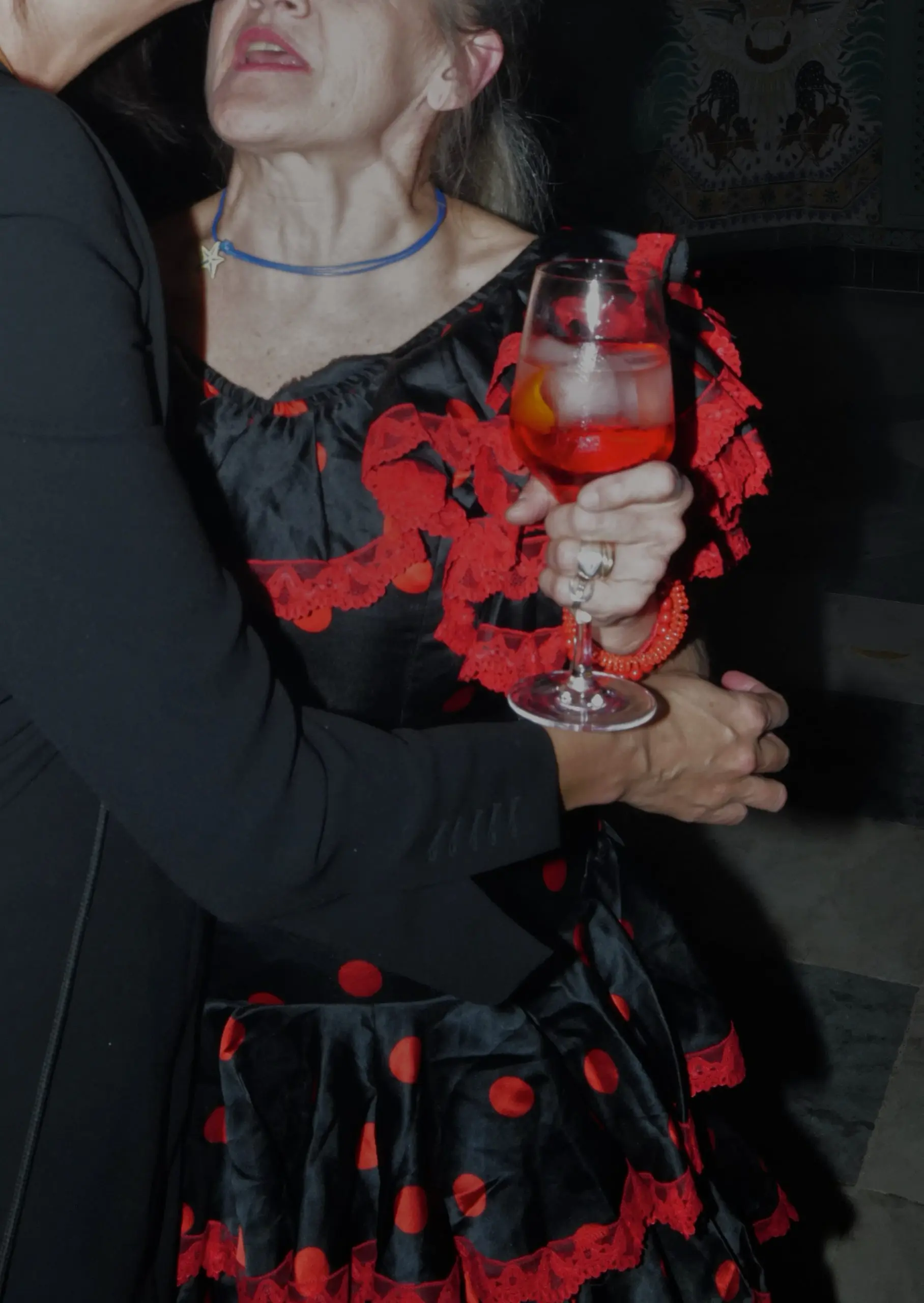 Señora vestida de flamenca sujentando una copa de campari