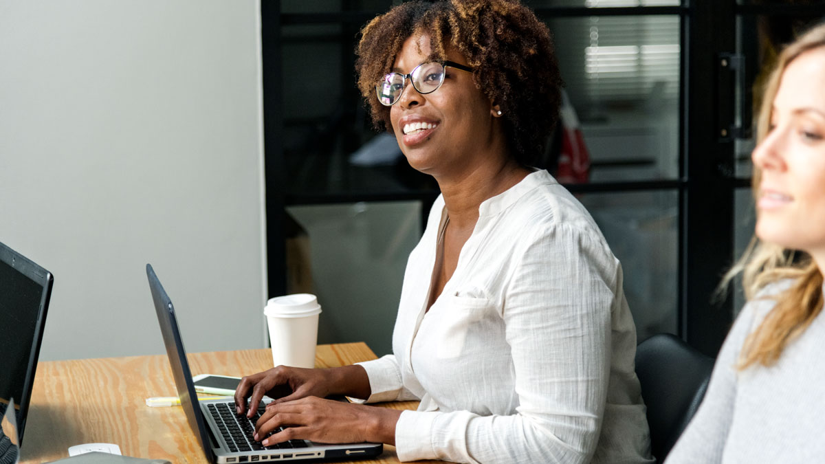 A woman sitting in a conference room during a hybrid meeting.