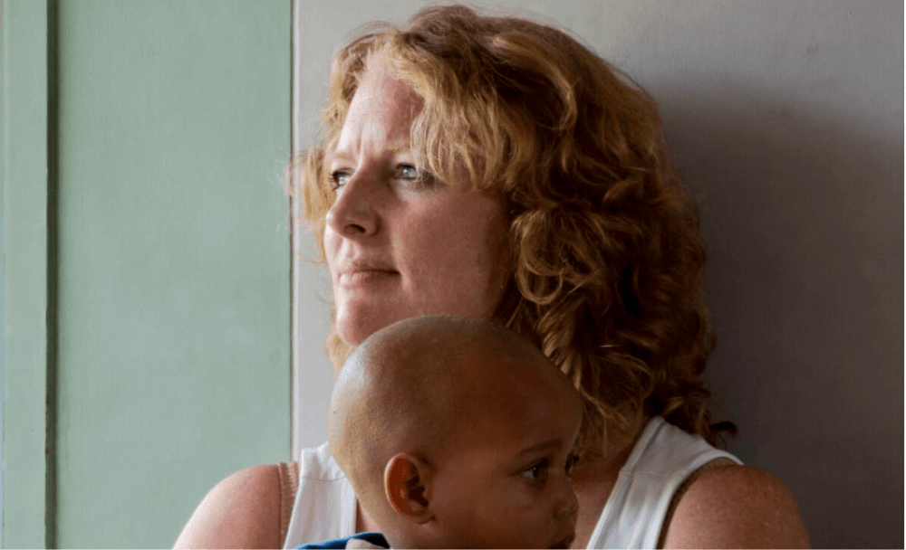 Sarah holding a child at the Plaster House.