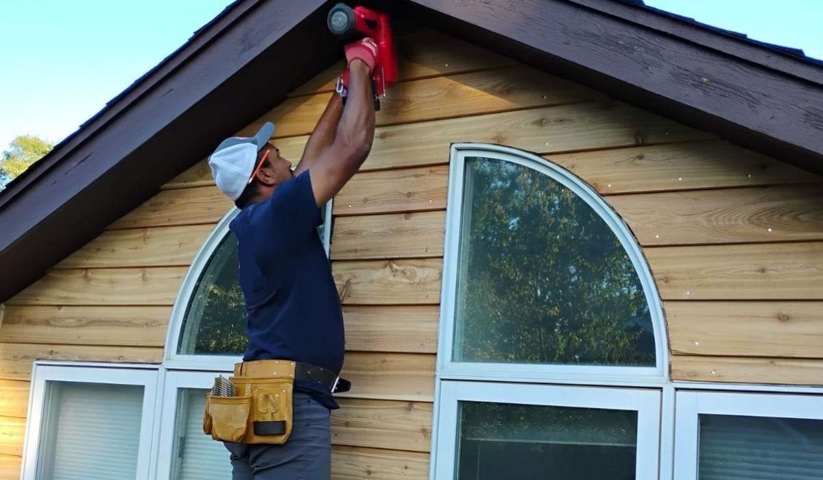 A contractor inspecting cedar siding on a Naperville home in preparation for winter