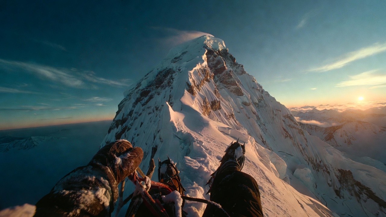 Smiling young man with short hair poses against a dark background, wearing a green button-up shirt.