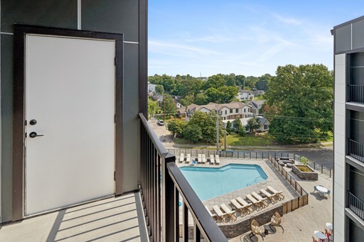 A balcony featuring a pool overlooks a vibrant city skyline under a clear blue sky.