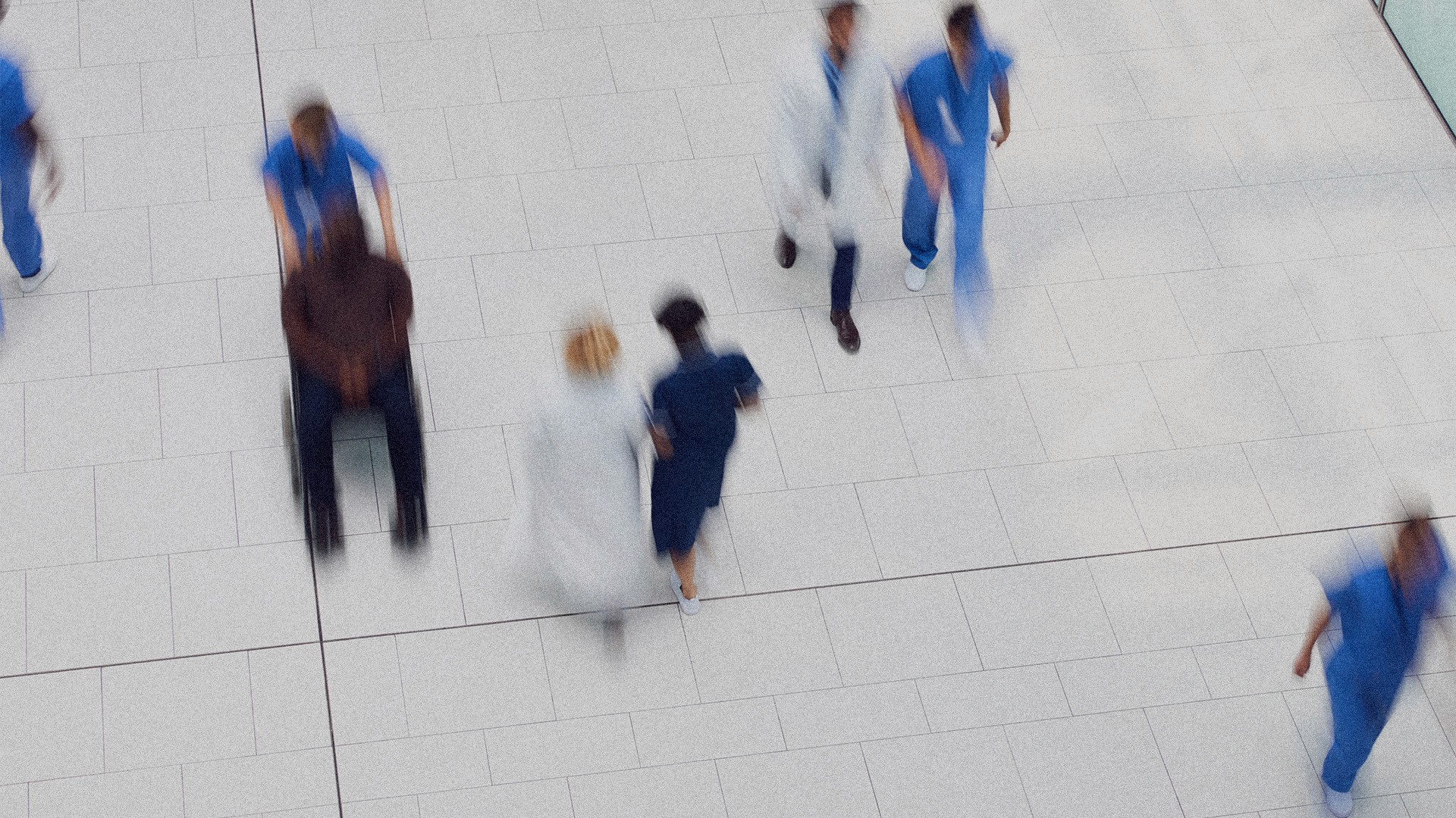 A grainy motion blur image of people walking on a hosptial floor.