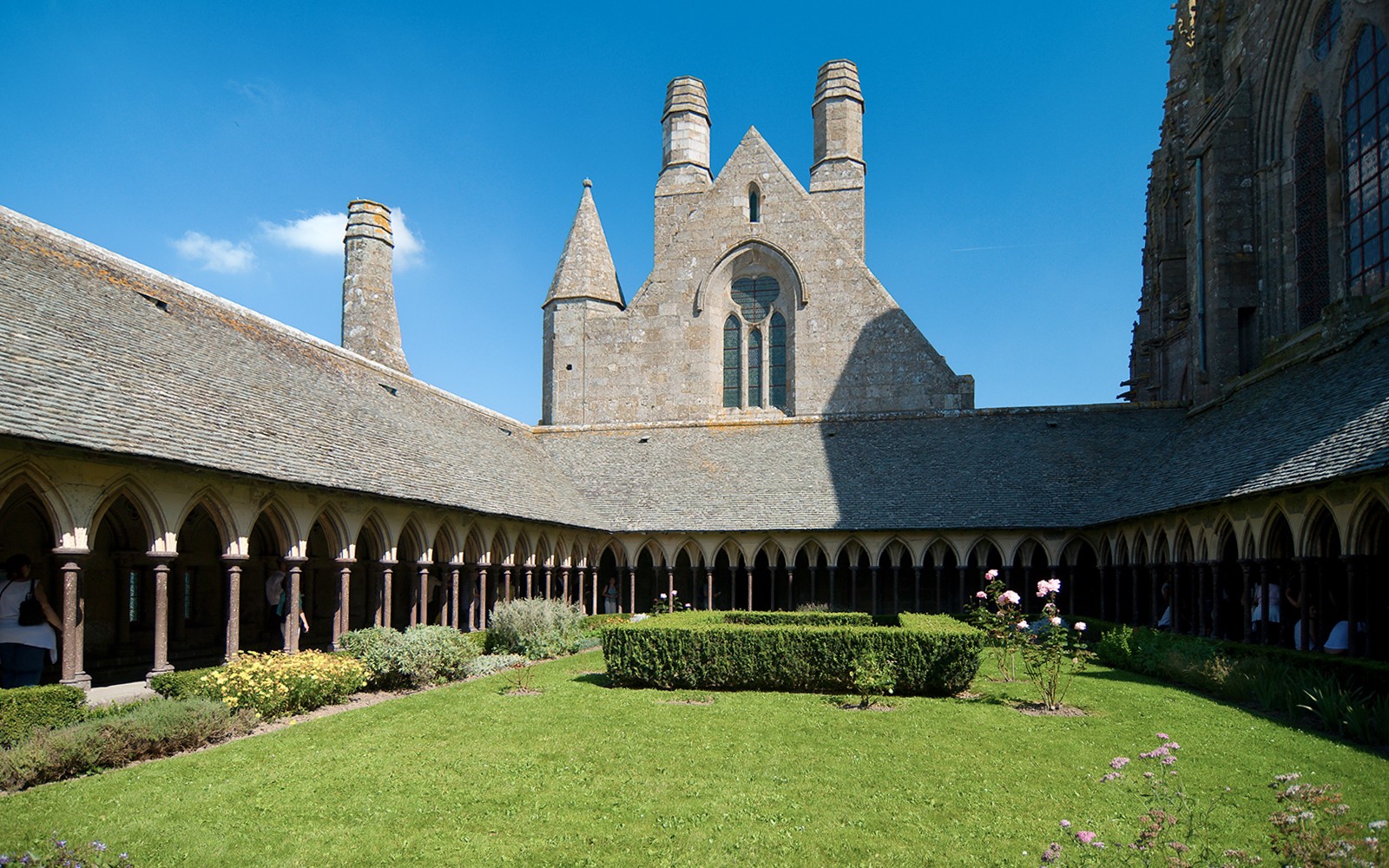 Cloister garden at Mont Saint Michel Abbey, France, under a clear blue sky.
