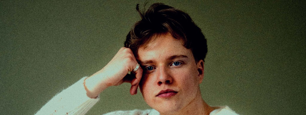 Close-up of a young blonde man looking directly at the camera