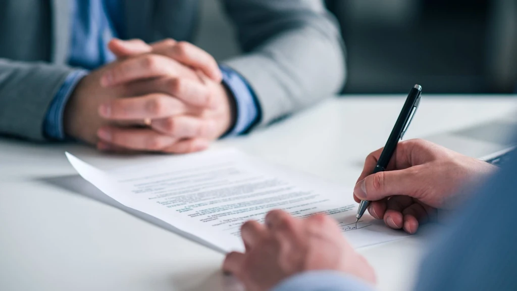 Zwei Personen prüfen Vertragsunterlagen am Tisch – Symbolbild für den Asset Deal