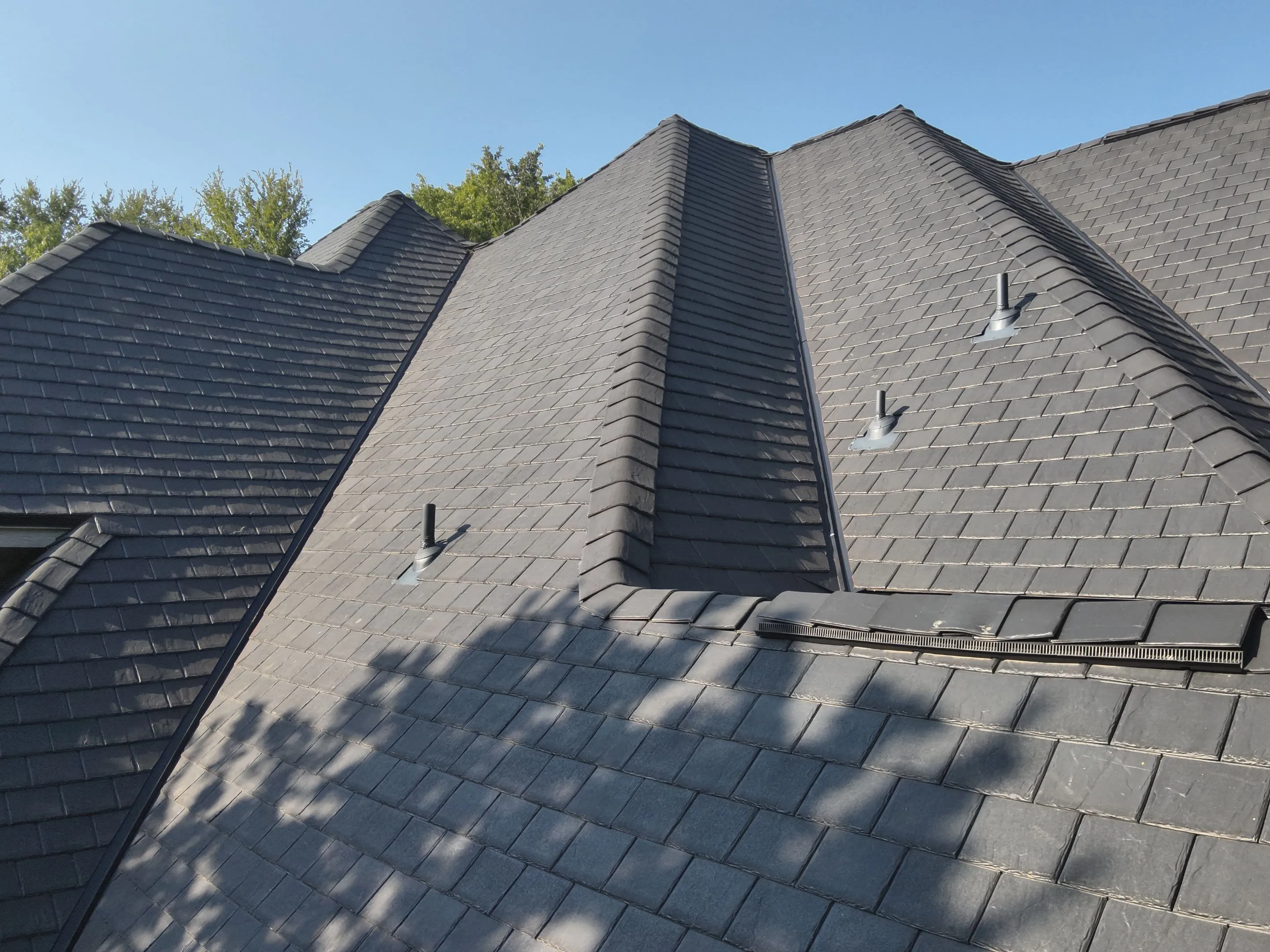 Steep gray shingle roof with multiple vents.