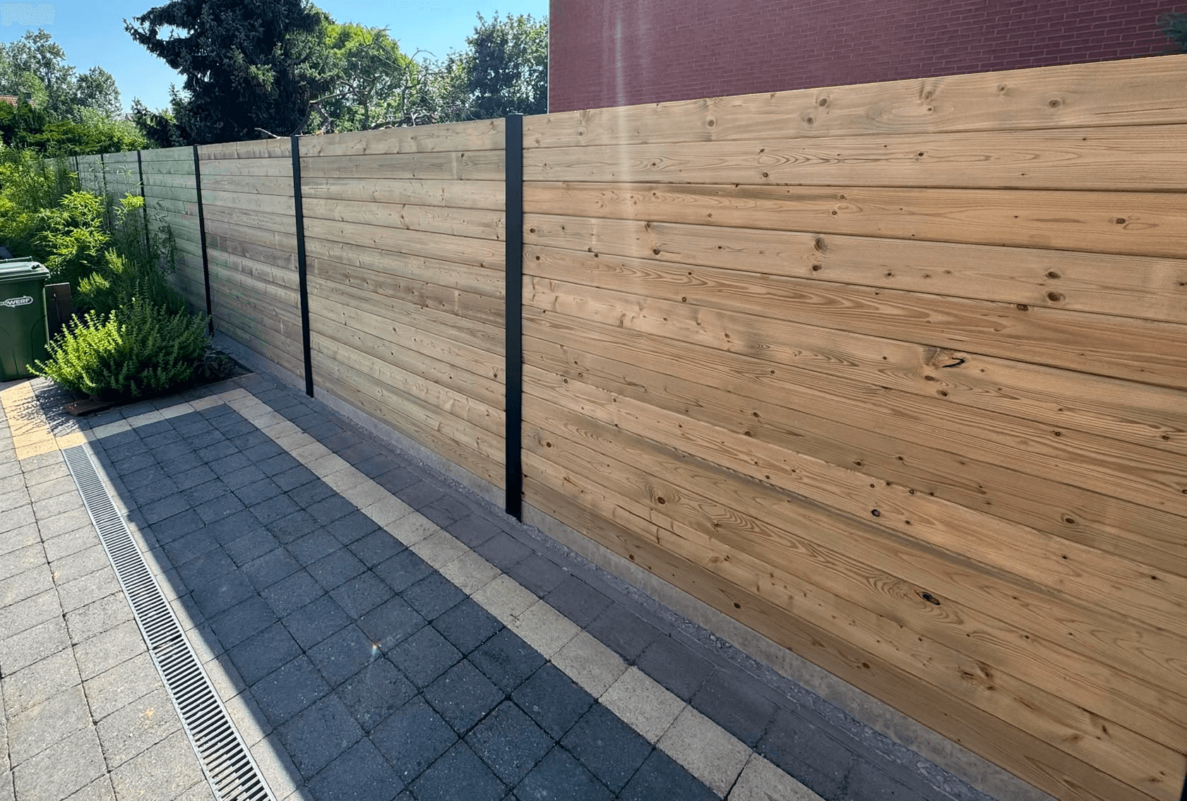 Houten tuinafsluiting met zwarte accenten — Afsluitingen in Wezemaal, gerealiseerd door Wilmaerts Tuinaanleg