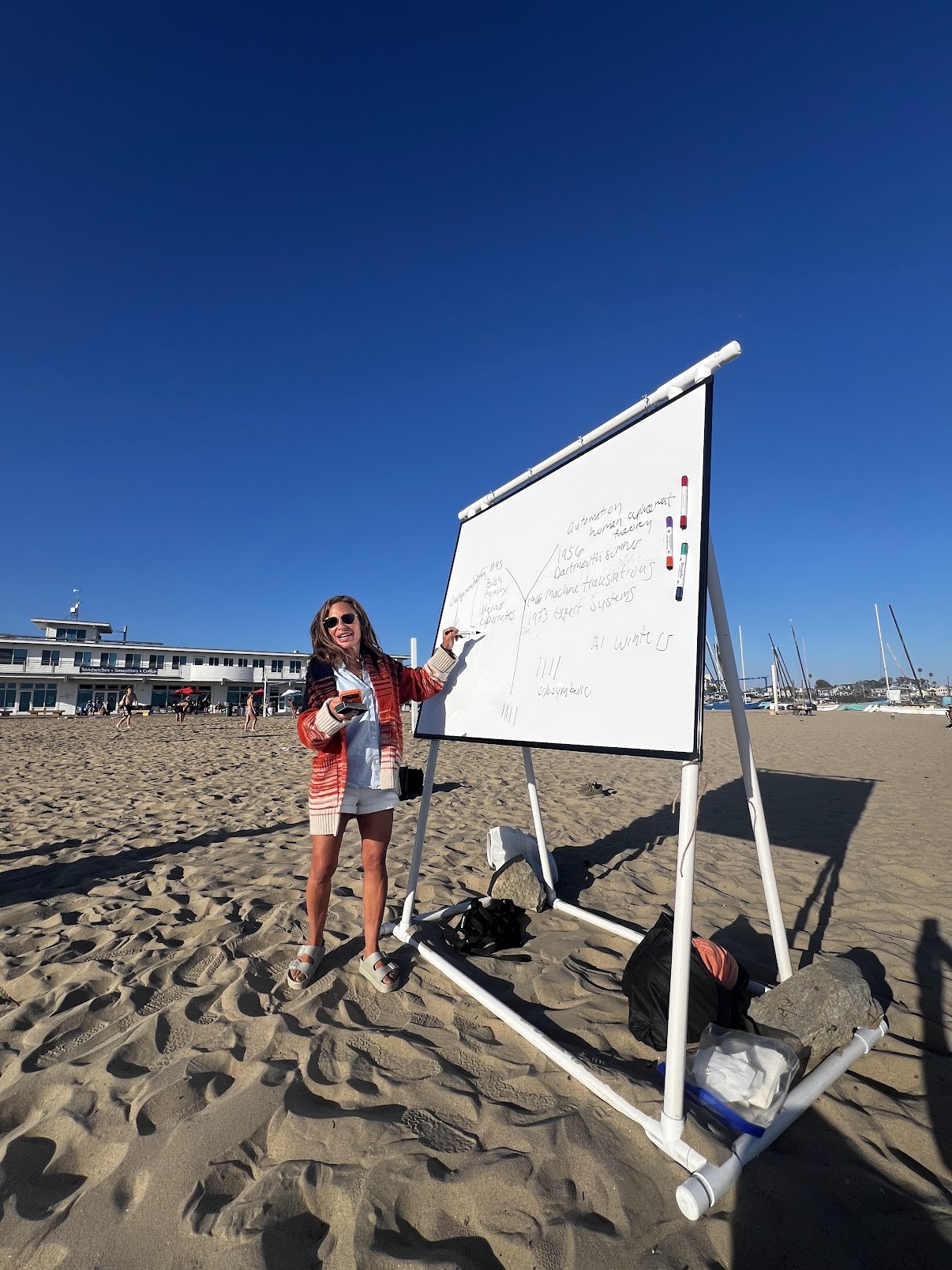 Jessica teaching beside a whiteboard on the beach