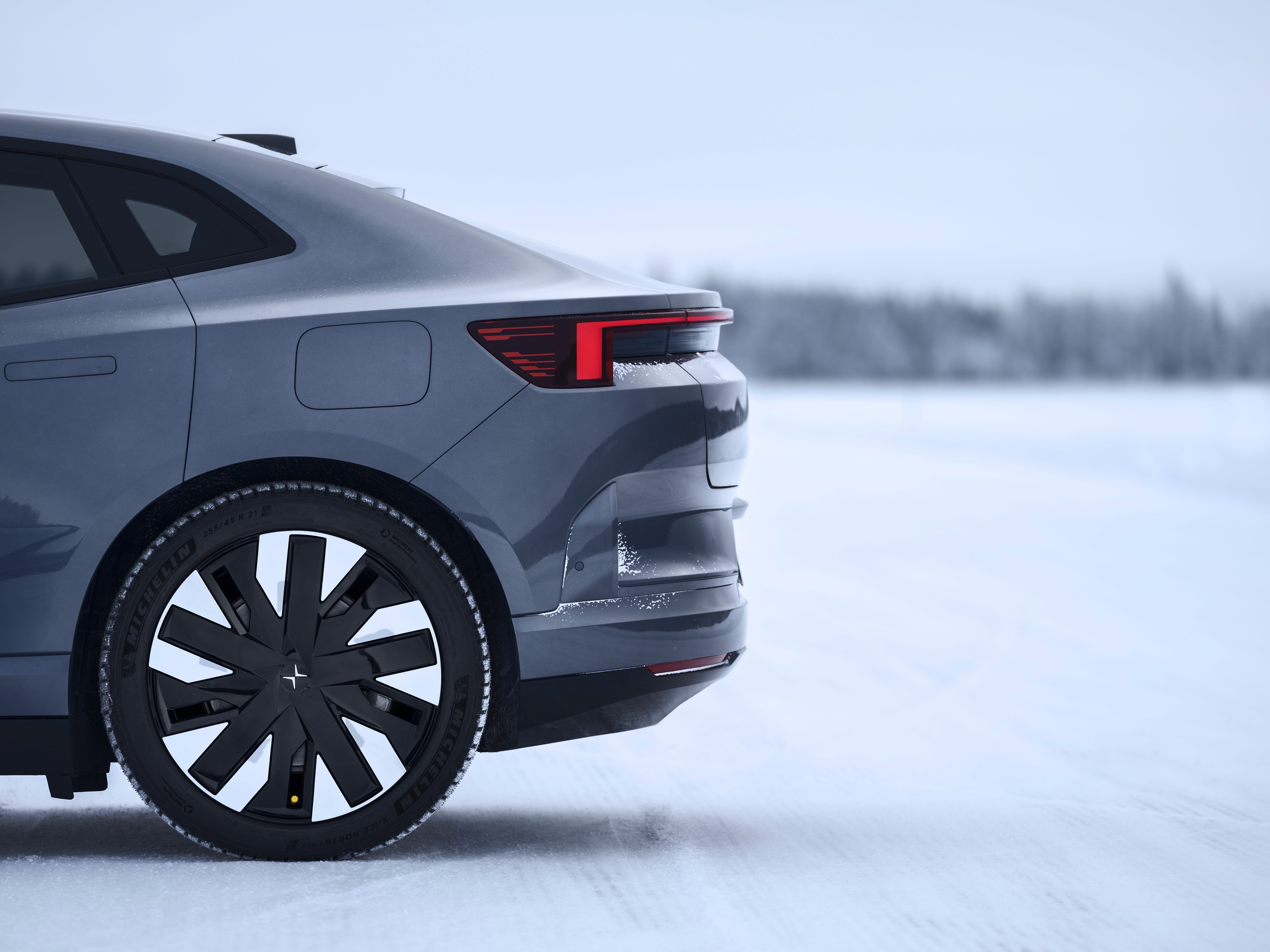Polestar 4 grise en conditions hivernales, SUV électrique sur route enneigée avec montagnes en arrière-plan