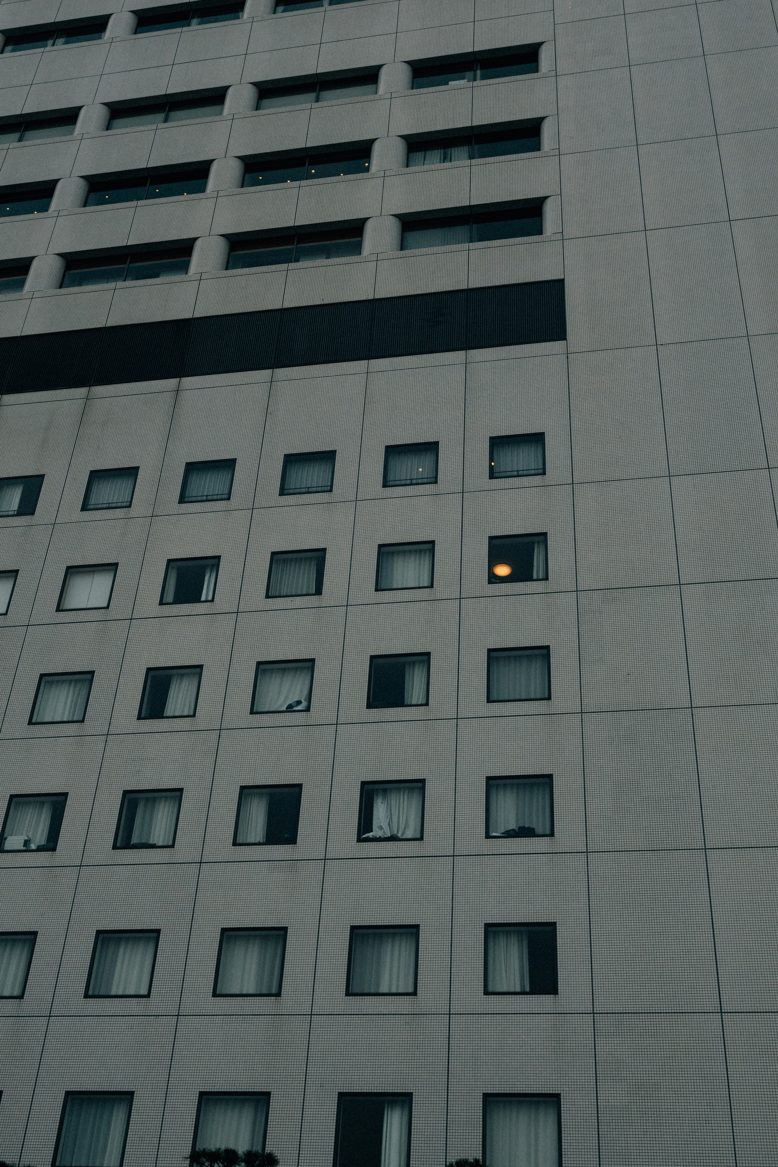 Modern building facade with many windows, one lit.