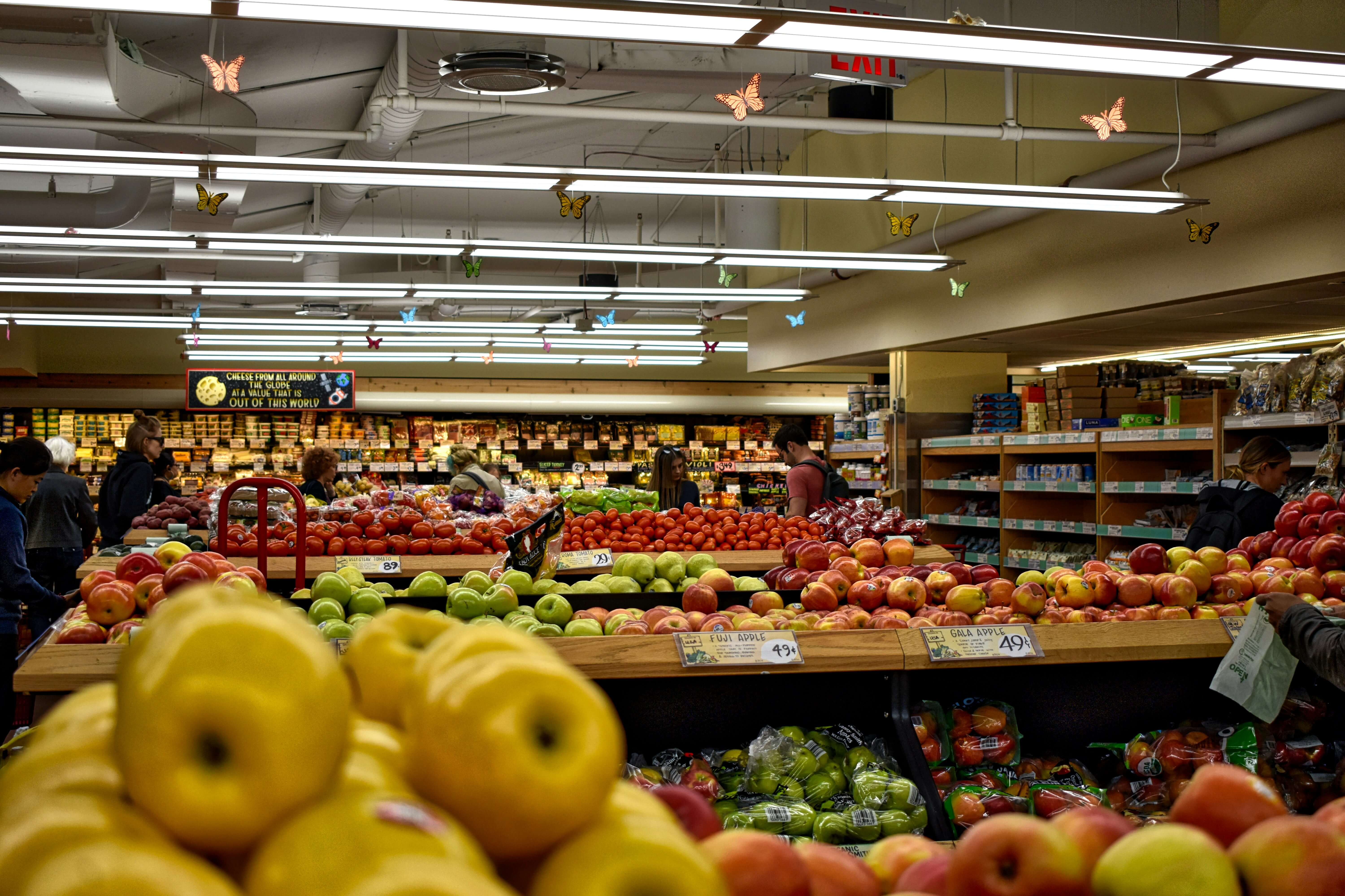 Shoppers browsing fresh fruit displays in a grocery store produce section.
