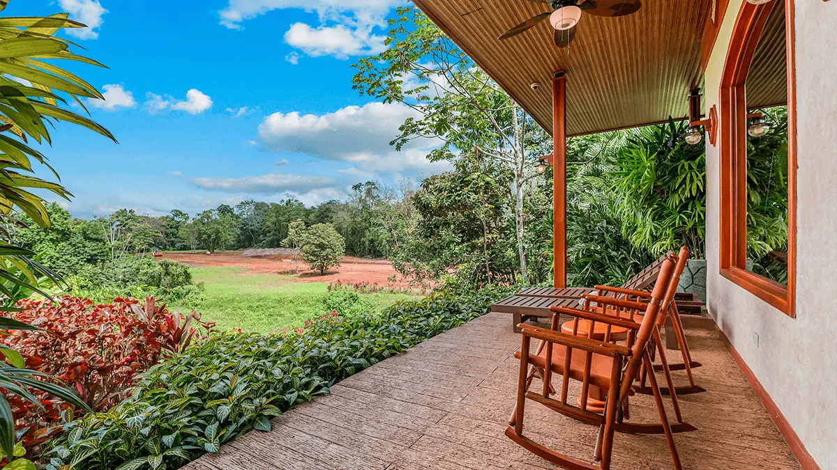 The covered terrace of an Arenal Hills villa with wooden rocking chairs, overlooking rainforest and gardens.