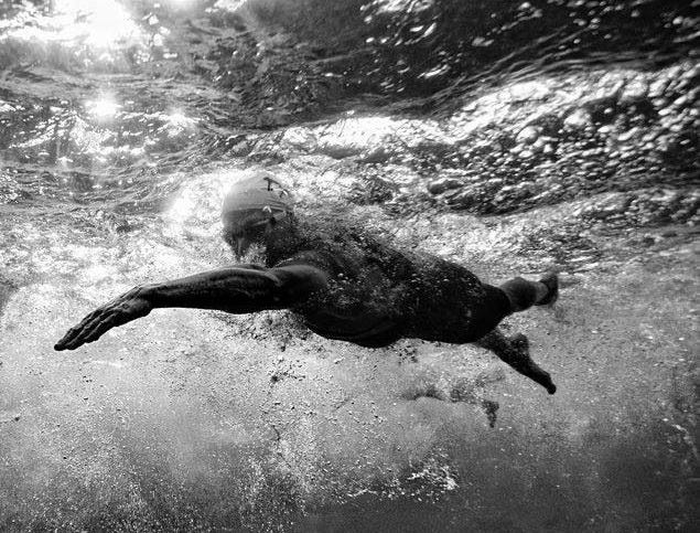 This may contain: a person swimming in the water with their head above the water's surface and sunlight shining on them