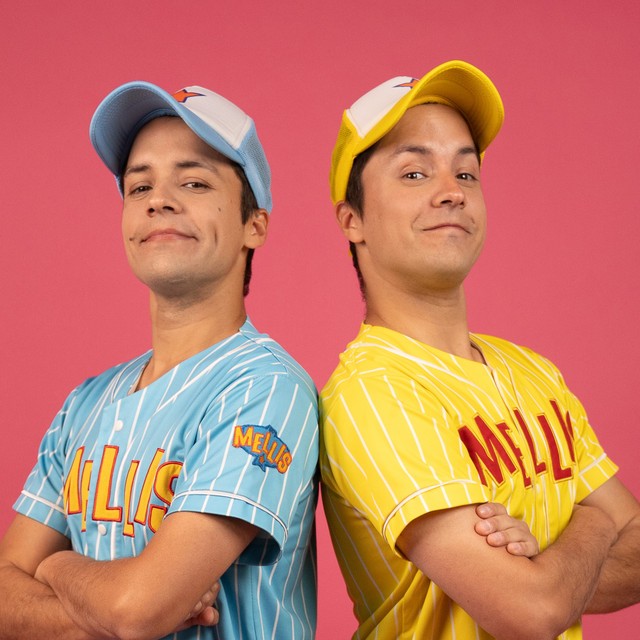 A person with short, curly blond hair wears a bright orange turtleneck sweater. The background is plain, creating a calm and focused portrait look.