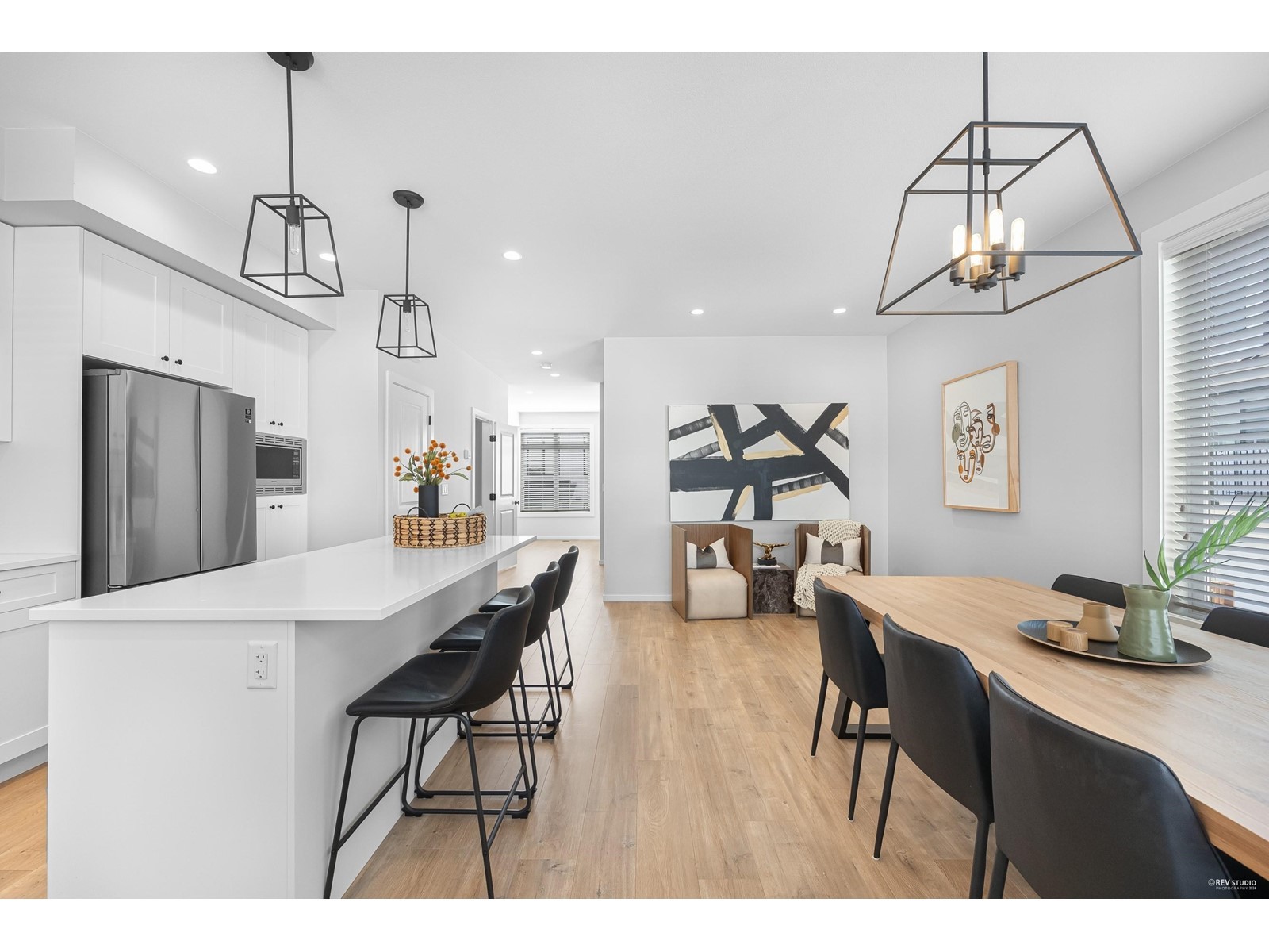 Bright, modern open-concept kitchen and dining area with sleek furniture and stylish lighting fixtures.