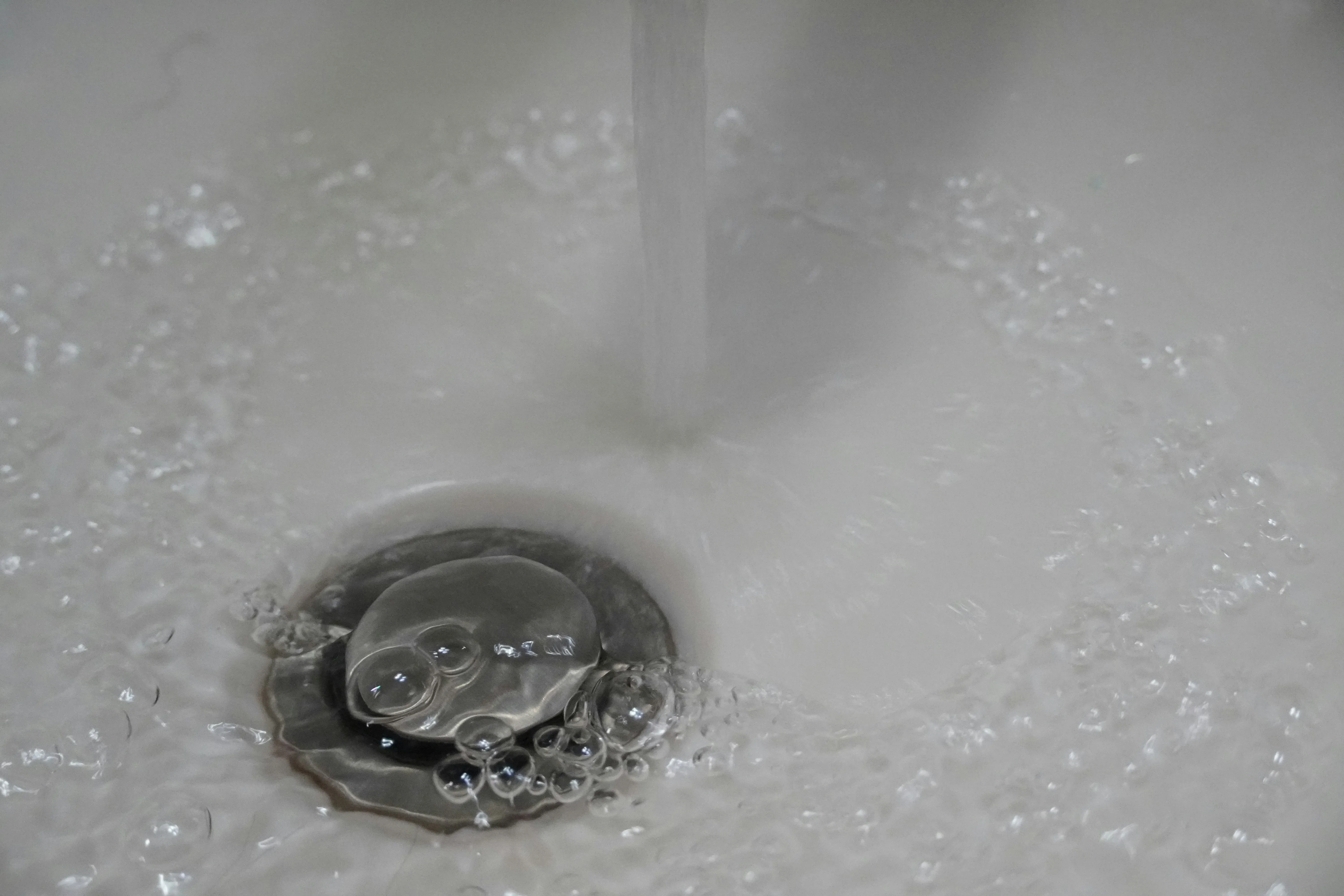Water pooling around the drain of a white sink