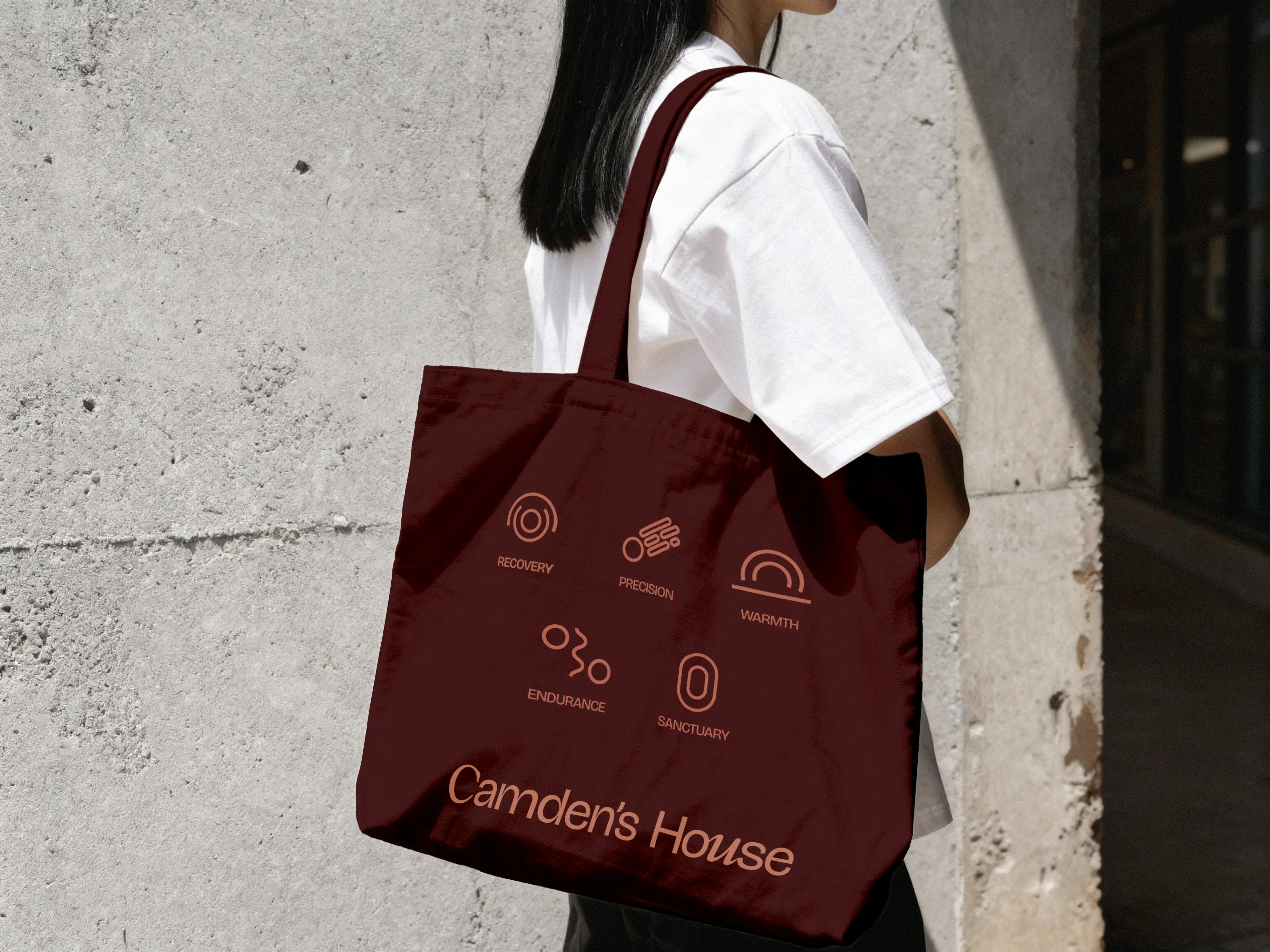 Camden's House brand identity — model wearing branded tote bag with custom iconography