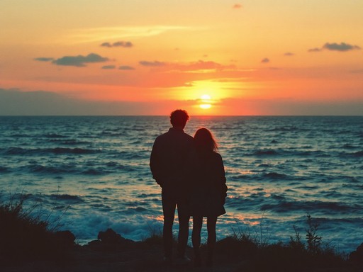 Silhouettes of a couple standing on a cliff overlooking the ocean at sunset.