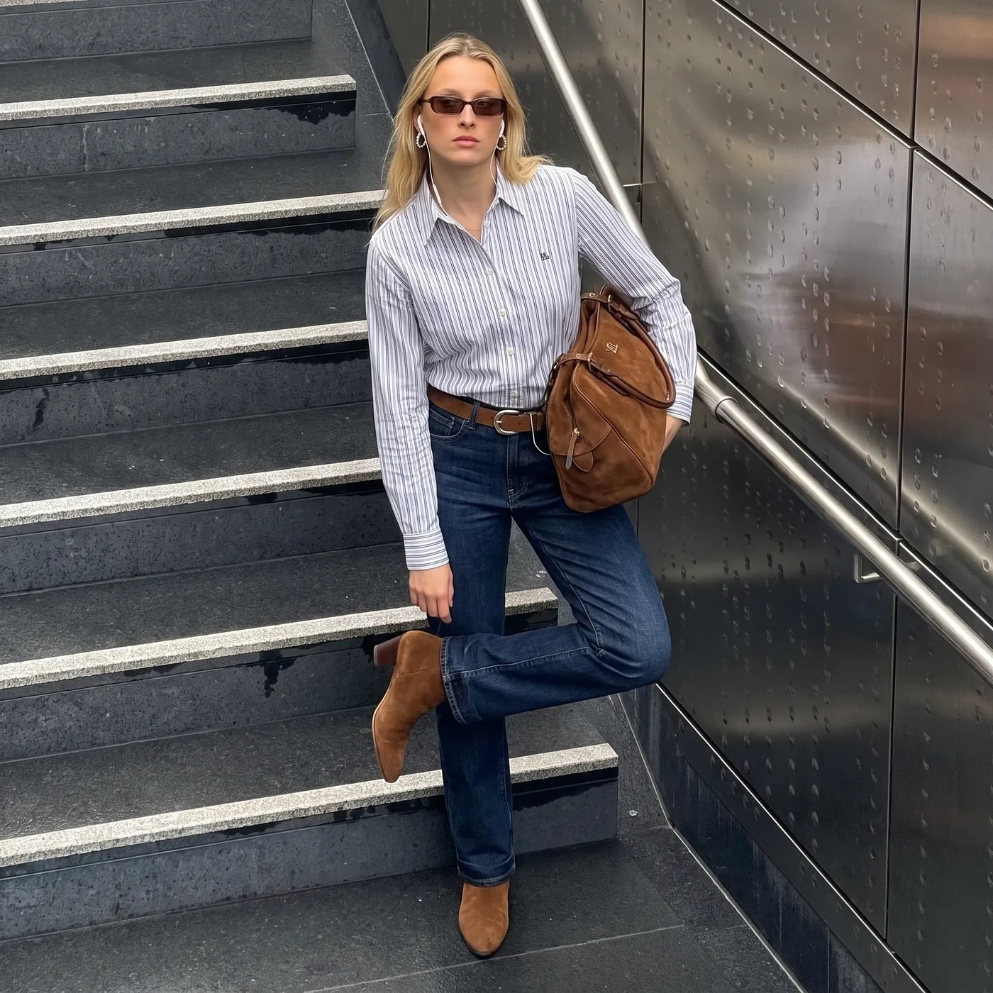 Foto della cliente sulle scale con camicia a righe e jeans
