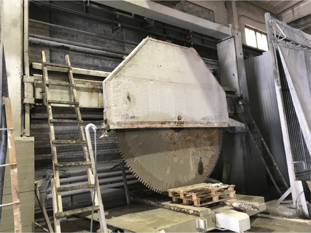 The Gantry Cutting Machine in action, showcasing its ability to handle large and rough stone blocks with its powerful blade, ensuring precise cuts in a rugged industrial environment.