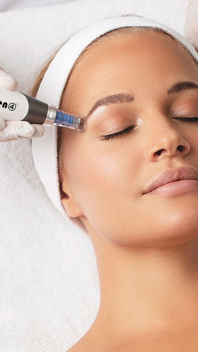 A woman lying down with a towel wrapped around her head, her face glowing with facial oil. She has a peaceful expression, enjoying a skincare treatment.