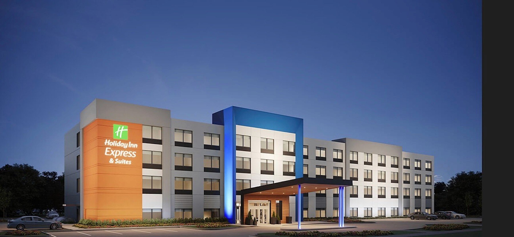 Holiday Inn Express & Suites hotel exterior illuminated at dusk, showcasing modern architecture and guest accommodations.