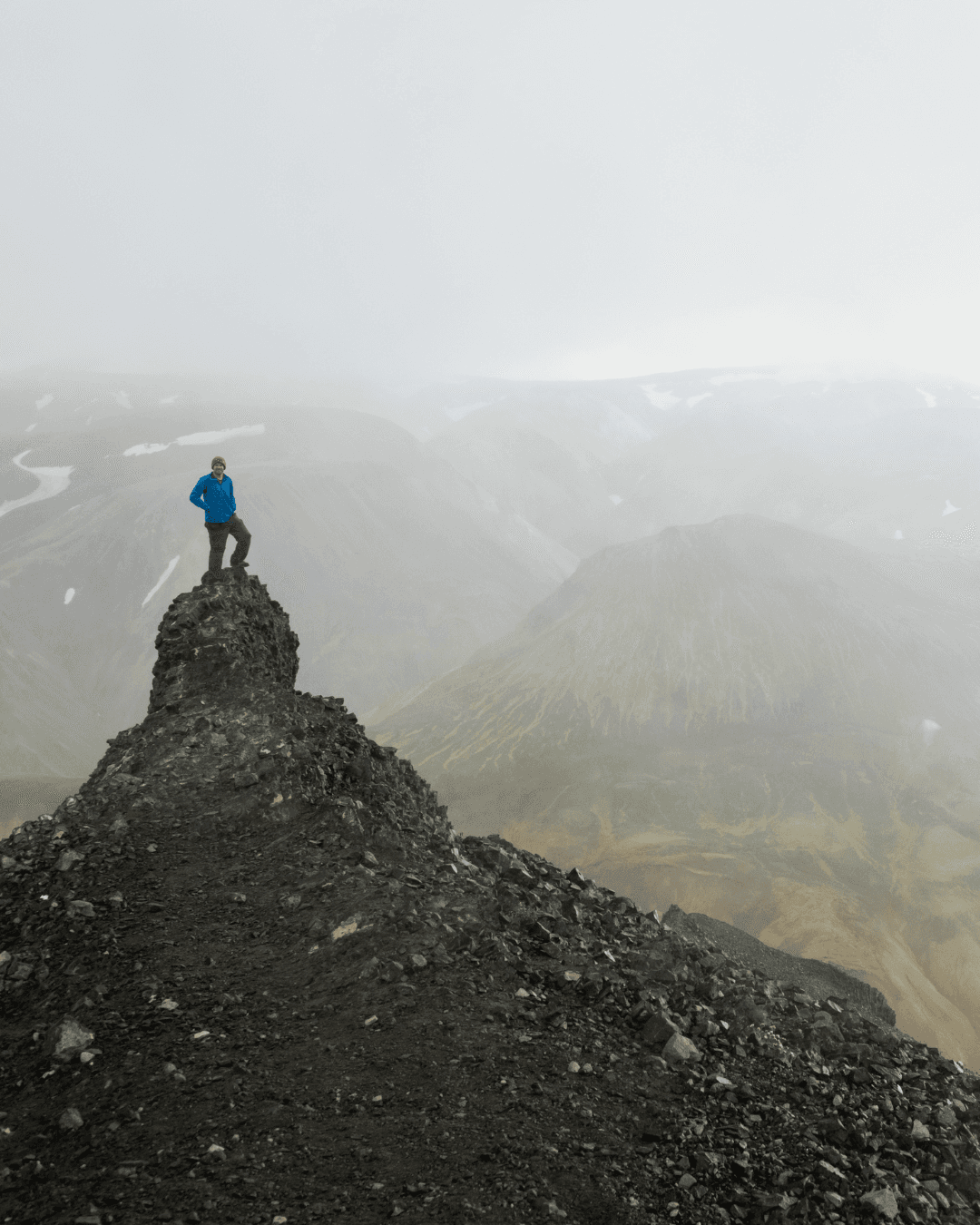 Hiker standing on a mountain ridge overlooking a wide natural landscape